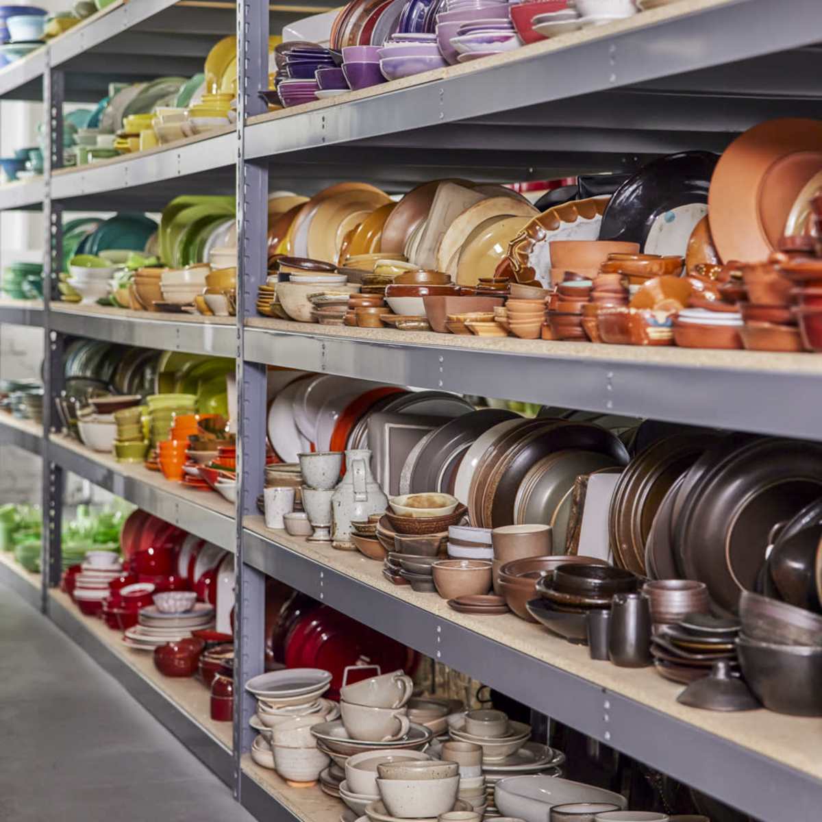 A storage area displays neatly arranged shelves filled with various types of colored dishes and cookware.