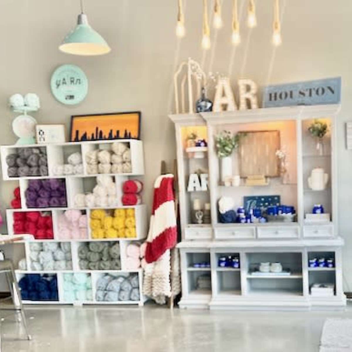 A cozy crafting space features shelves filled with colorful yarn, a decorative cabinet, and various crafting supplies arranged throughout the room.