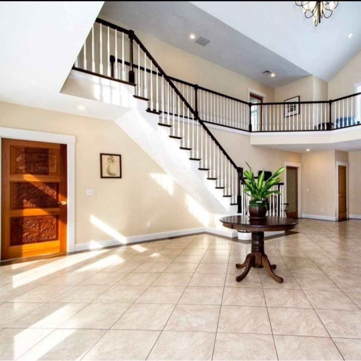 A spacious foyer with a two-story staircase, tiled floor, and large windows allowing natural light.