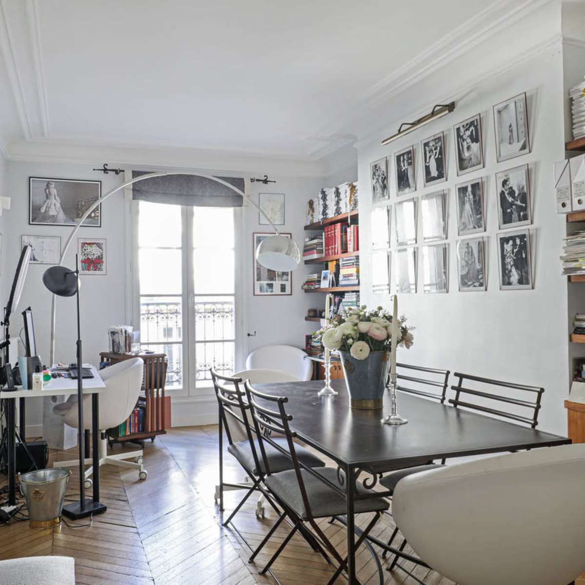 A well-organized office features a large table surrounded by chairs, shelves filled with binders and books, and large windows allowing natural light to illuminate the space.