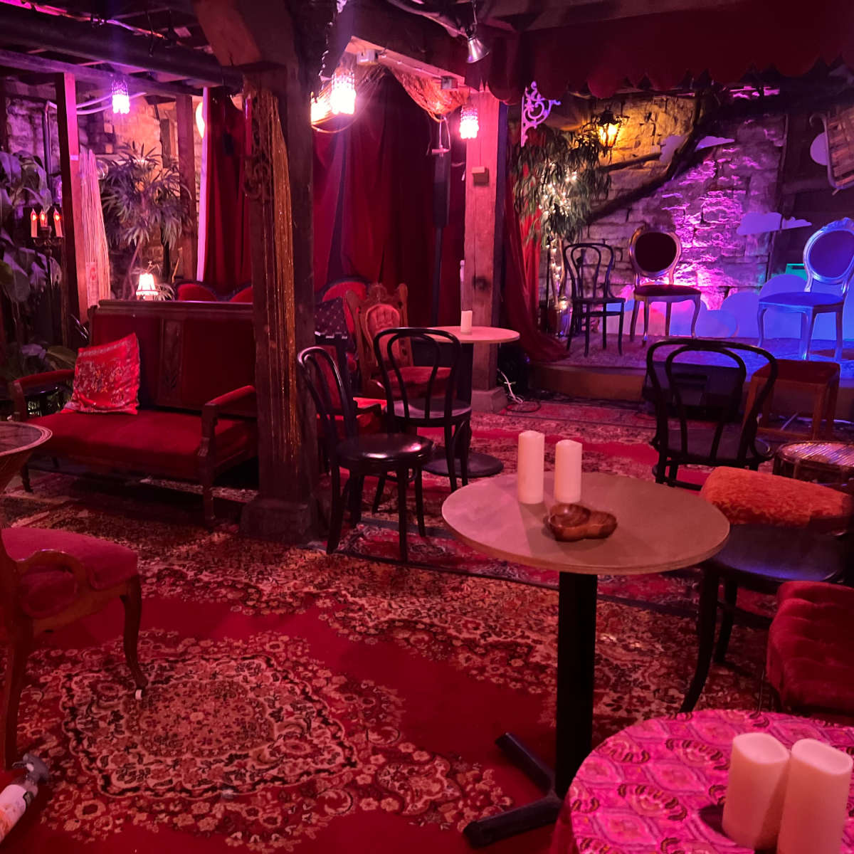 A cozy lounge area with plush seating, tables, and soft lighting, surrounded by plants and decorative elements.