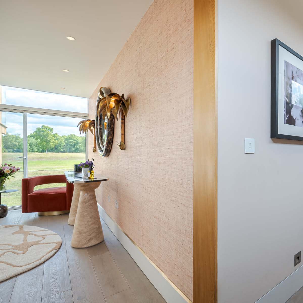 A hallway features a decorative table with a vase of flowers on one side and a series of framed photographs on the opposite wall.