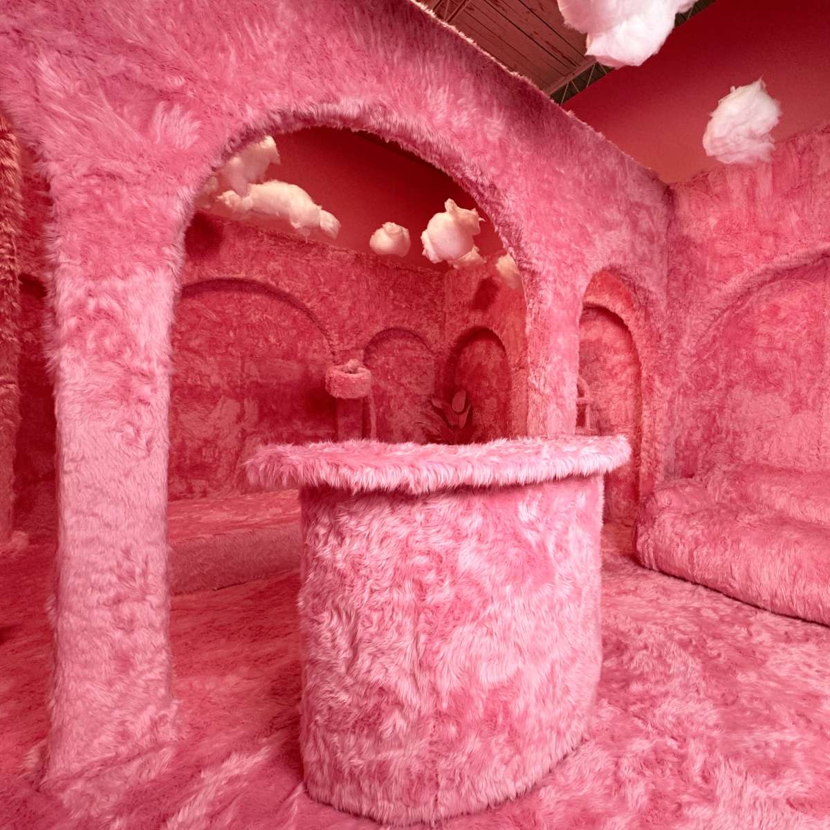 An interior space featuring walls, furniture, and decorations covered in bright pink, fuzzy material.