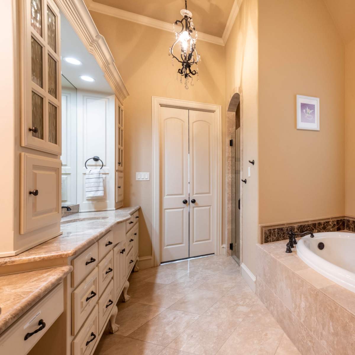 A bathroom featuring a bathtub, tiled floor, and a light-colored vanity with ample storage.