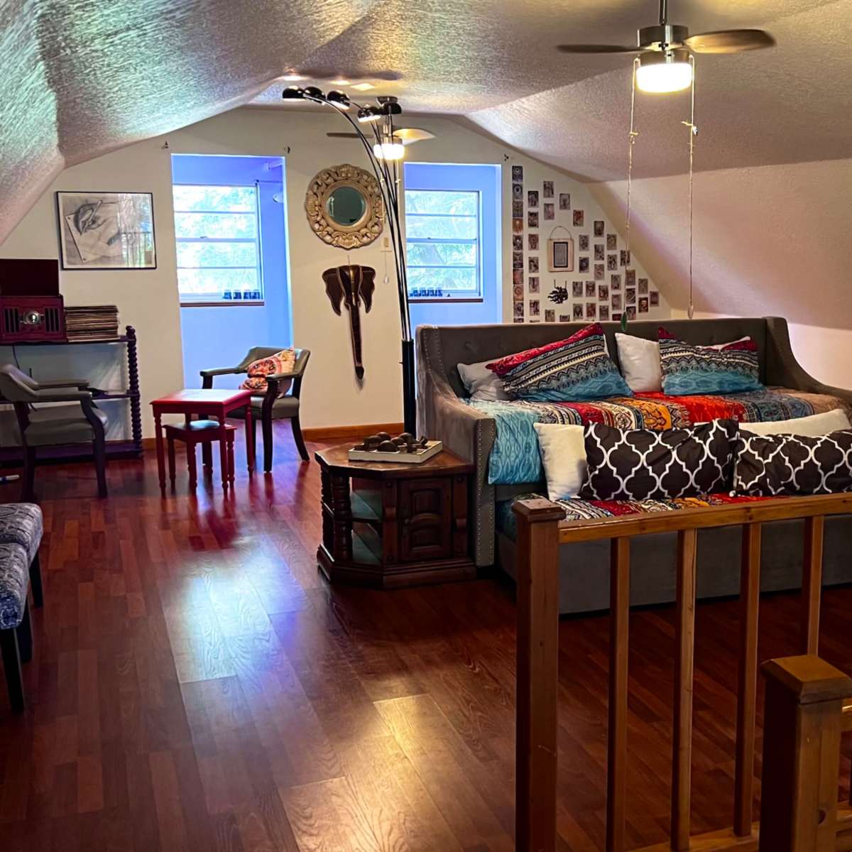 A cozy, furnished loft space with a bed, a seating area, and various decorative elements on the walls.