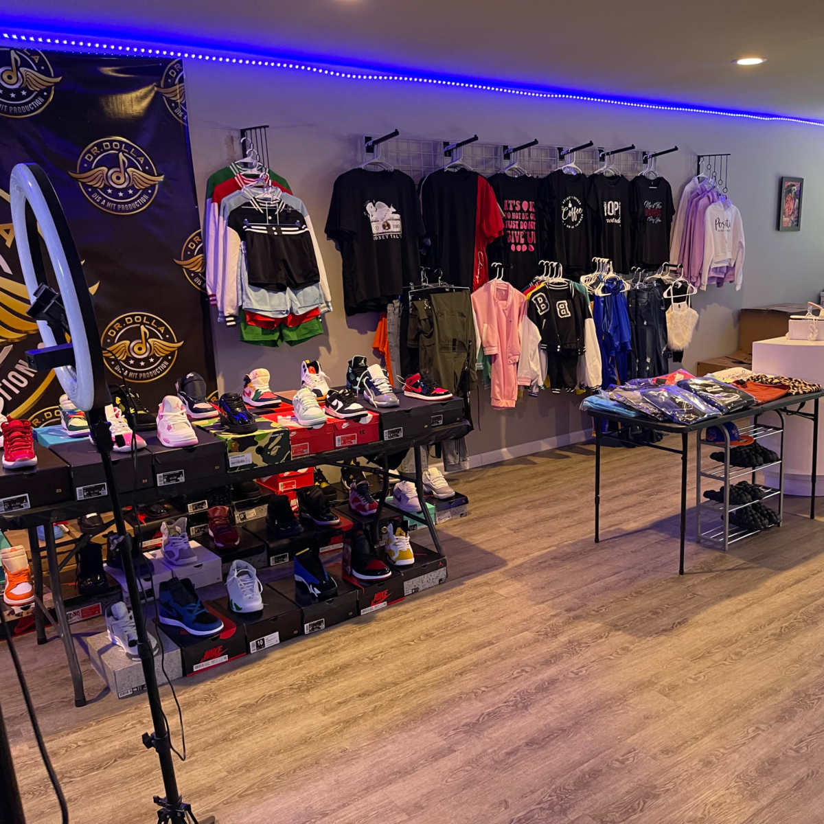A modern retail space showcasing various clothing and sneaker items displayed on racks and tables, with vibrant lighting accentuating the merchandise.