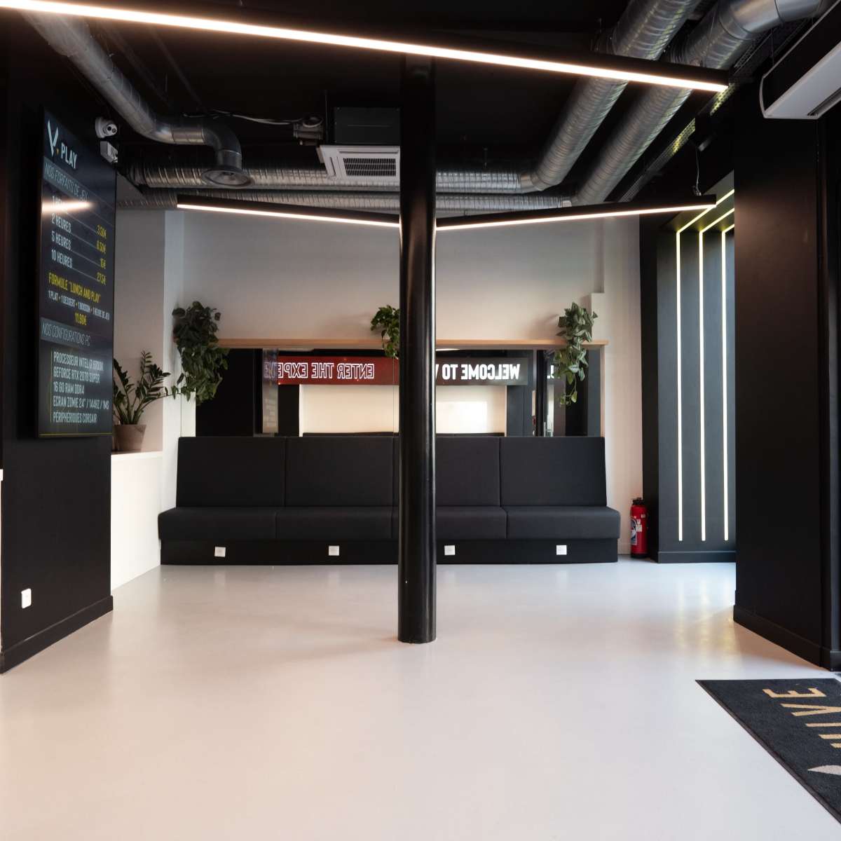 A modern reception area with black walls, a large seating area, and a glass entrance door.