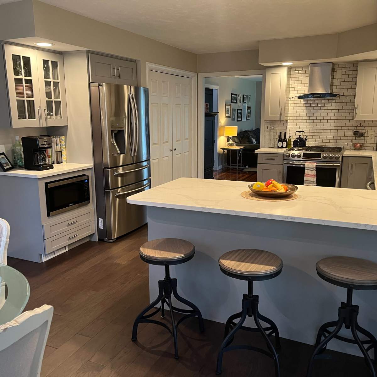 A modern kitchen with a central island, stainless steel appliances, and a dining area featuring a glass table and white chairs.