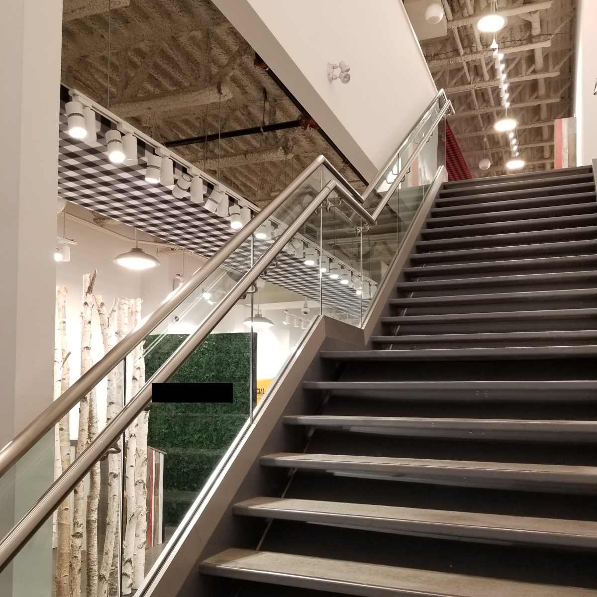 A modern staircase with metal railings leads to an upper level in a contemporary indoor space.