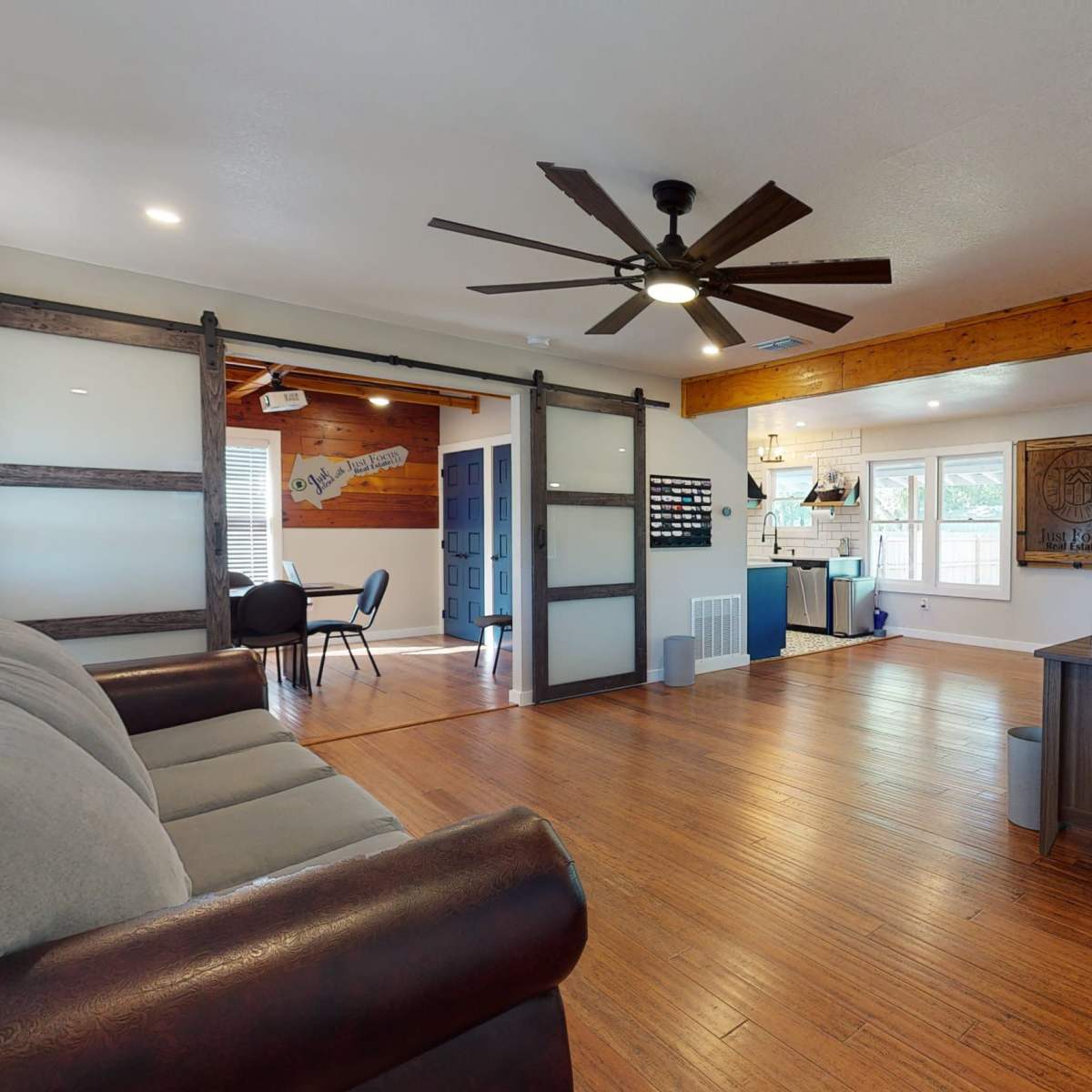 A welcoming reception area with a sofa, a front desk, and sliding glass doors leading to another room.