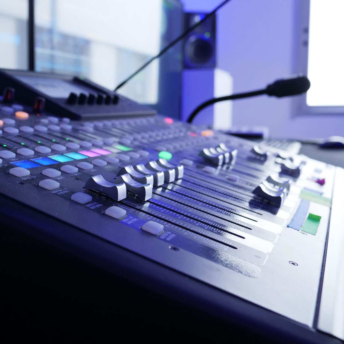A close-up of a digital audio mixing console featuring colorful buttons and sliders, set in a modern studio environment.