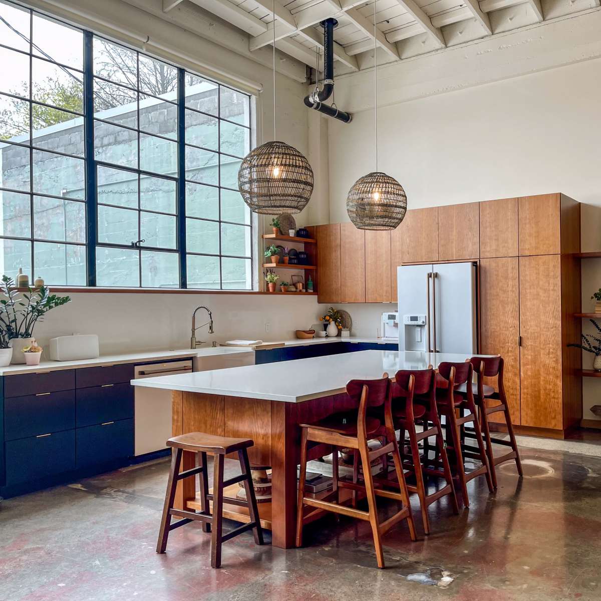 The kitchen features a large island with seating, modern appliances, and a combination of wooden cabinetry and open shelving.