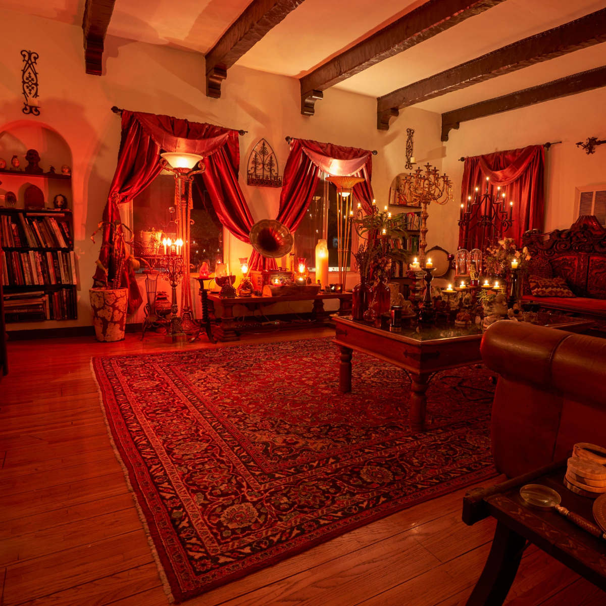 The scene depicts a warmly lit living room adorned with rich curtains, ornate furniture, and multiple candles creating a cozy ambiance.