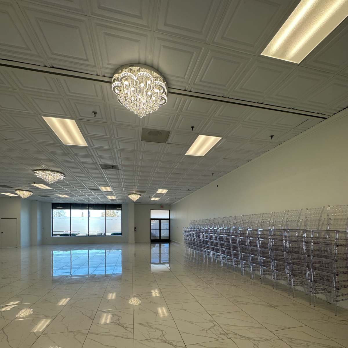 A spacious, empty room with marble flooring and rows of clear display bins along one wall.