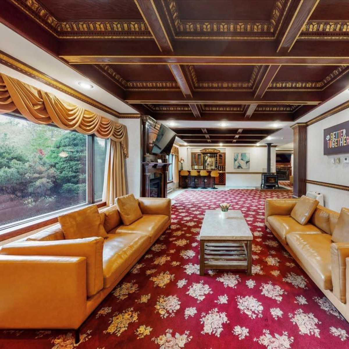 A spacious living area featuring two leather sofas, a coffee table, and large windows with draped curtains.