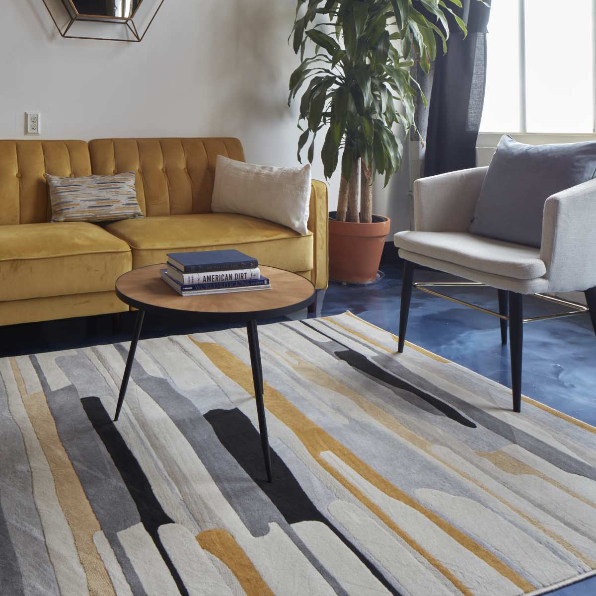 A modern living room with a yellow tufted sofa, two white armchairs, a round coffee table, and a striped area rug.