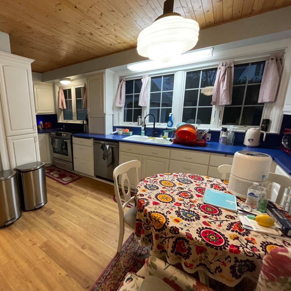 The kitchen features white cabinetry, blue countertops, and a circular table covered with a patterned tablecloth.
