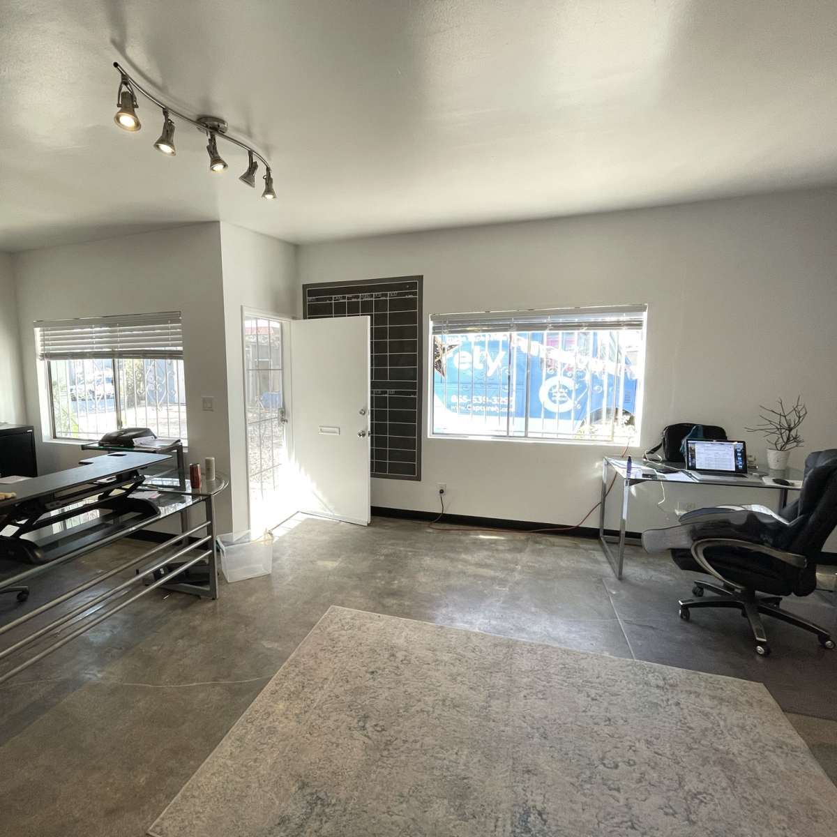 A modern office space with a desk, chair, and large windows allowing natural light in.