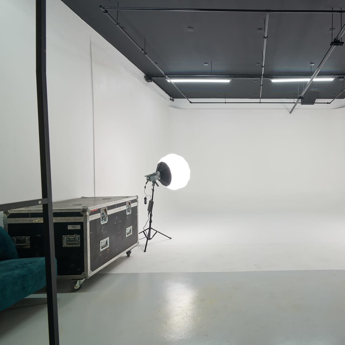 A minimalistic studio space with two large softbox lights positioned on either side of the room and a storage case in the foreground.