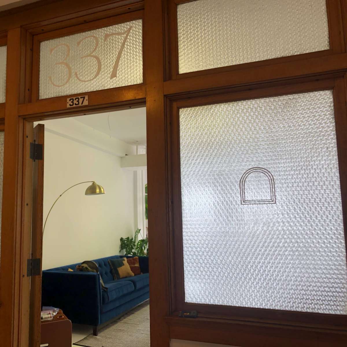 The entrance to room 337, featuring frosted glass windows and a glimpse of a blue sofa and a lamp inside.