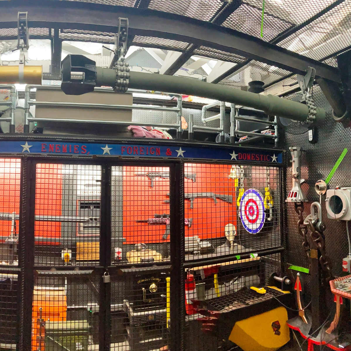 A workshop or storage area filled with various tools, equipment, and a distinctive, large cylindrical object mounted on the wall.