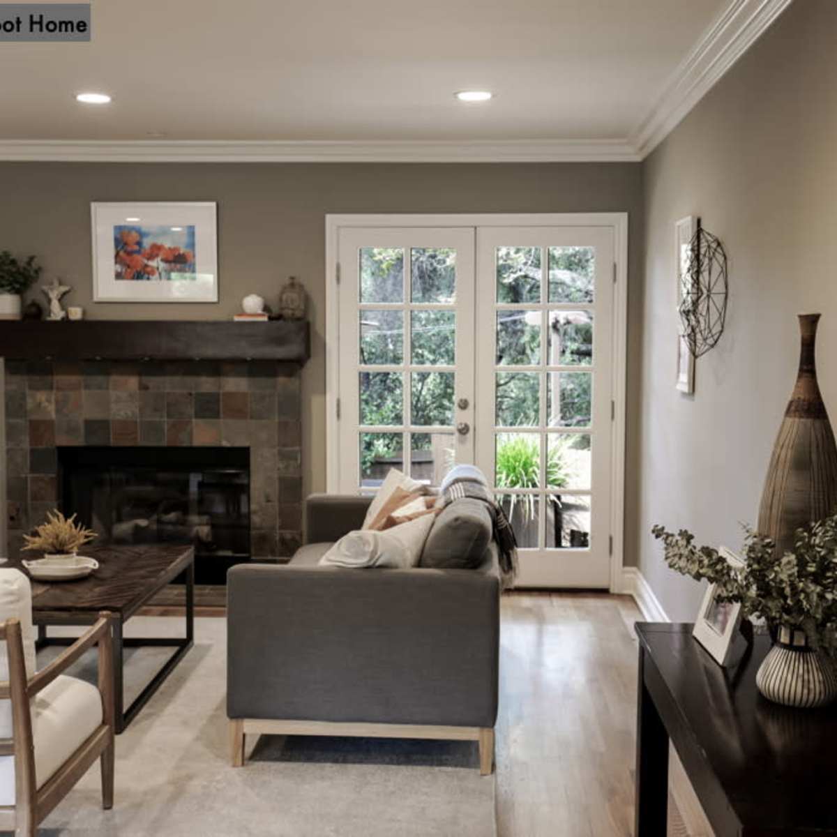 A living room with a fireplace, a coffee table, and large glass doors opening to an outdoor space.