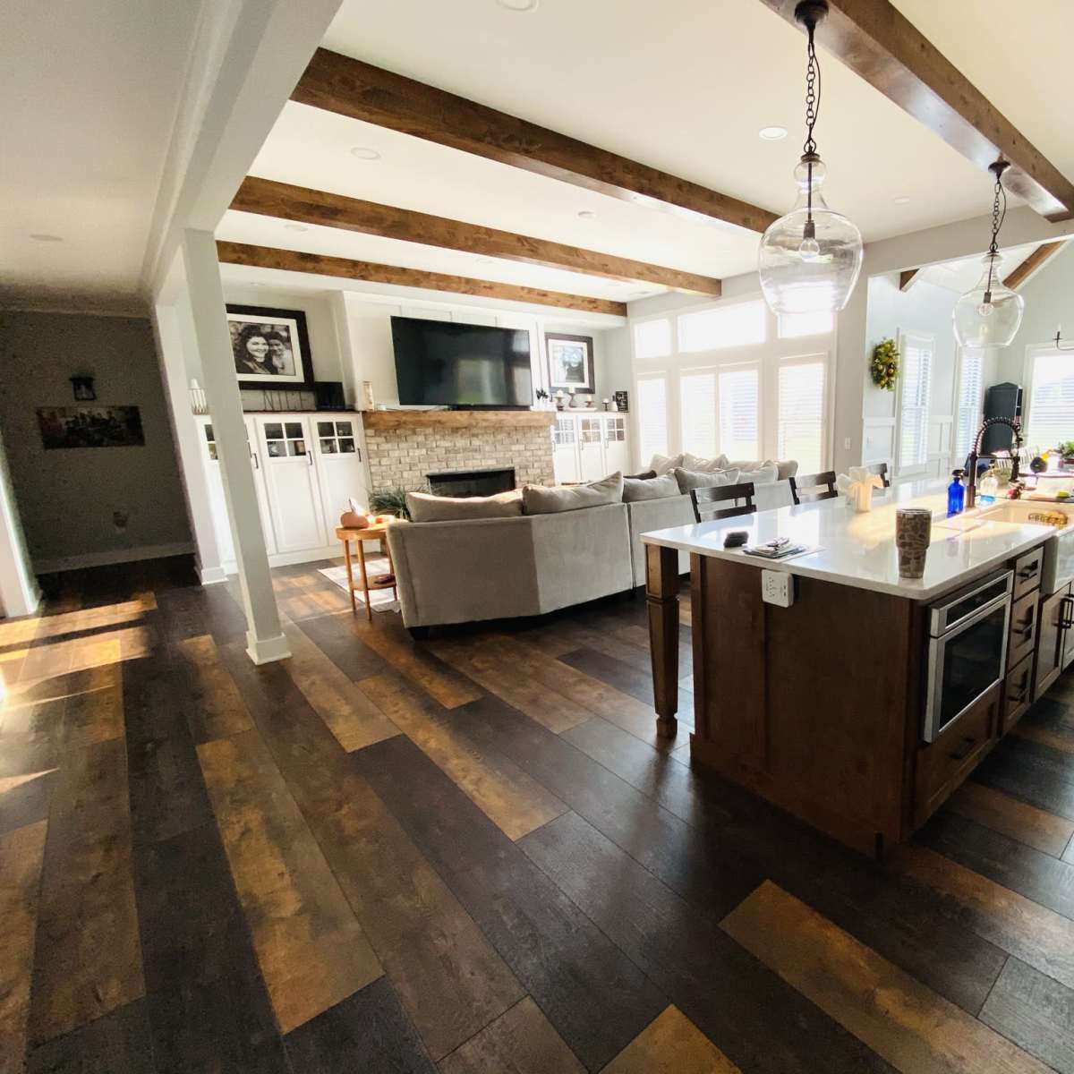 A spacious living area features a modern kitchen island, a seating area with a sectional sofa, and large windows allowing natural light to fill the room.
