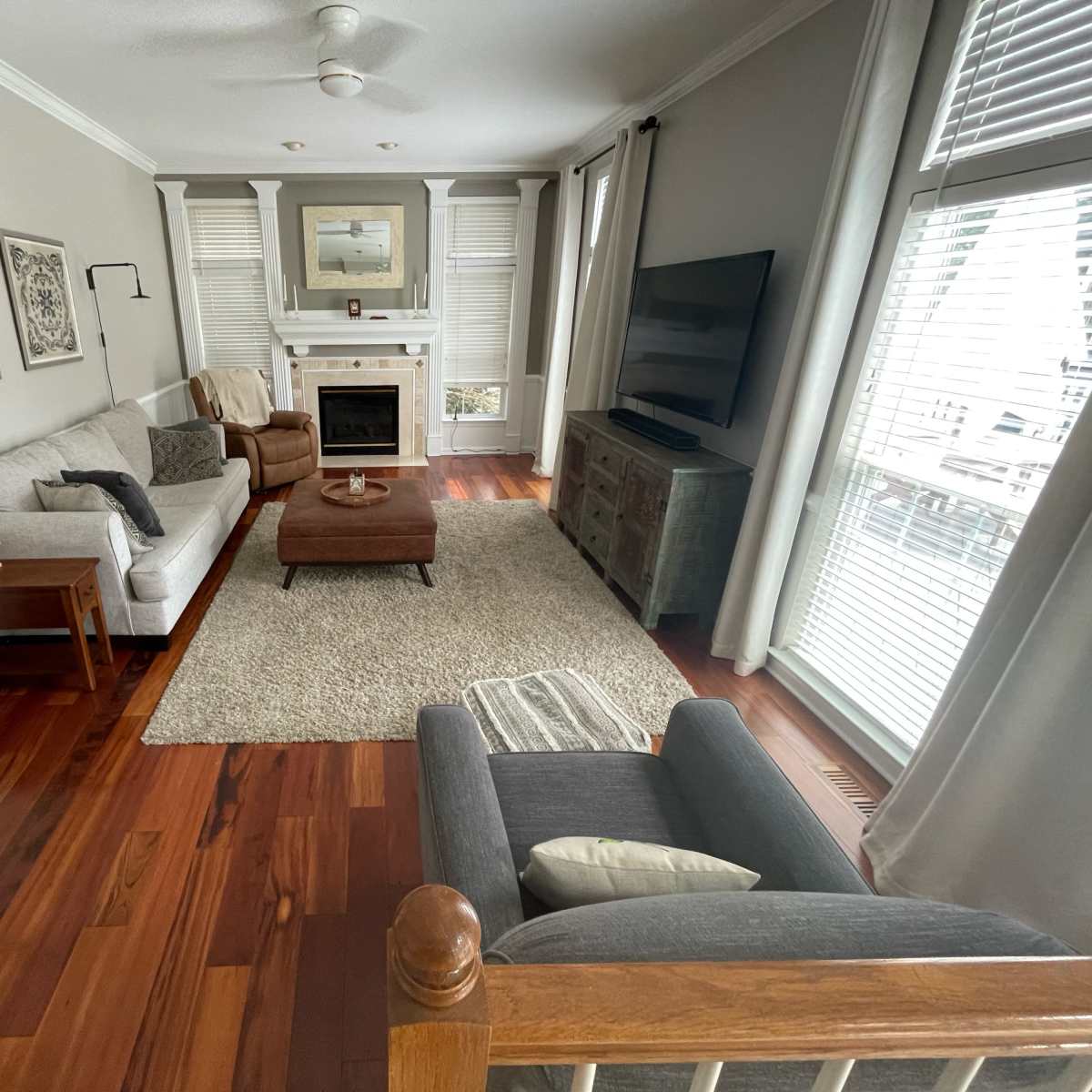 A living room with a couch, chair, and a coffee table centered on a large area rug, featuring a fireplace and a television against the wall.