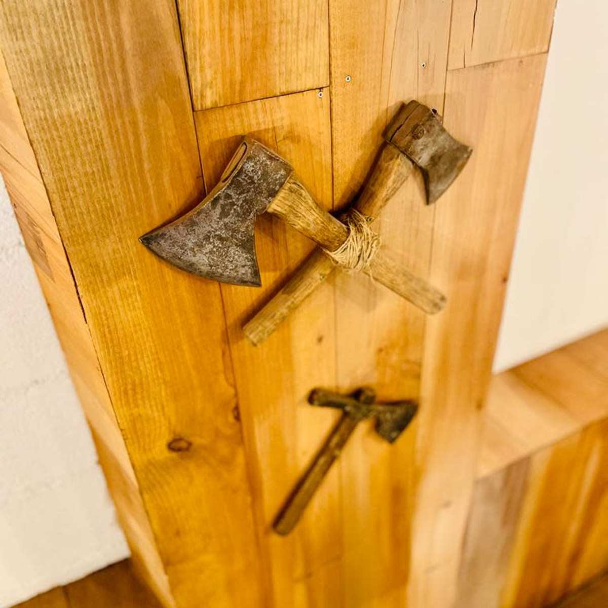 Two crossed axes and a smaller axe mounted on a wooden wall.