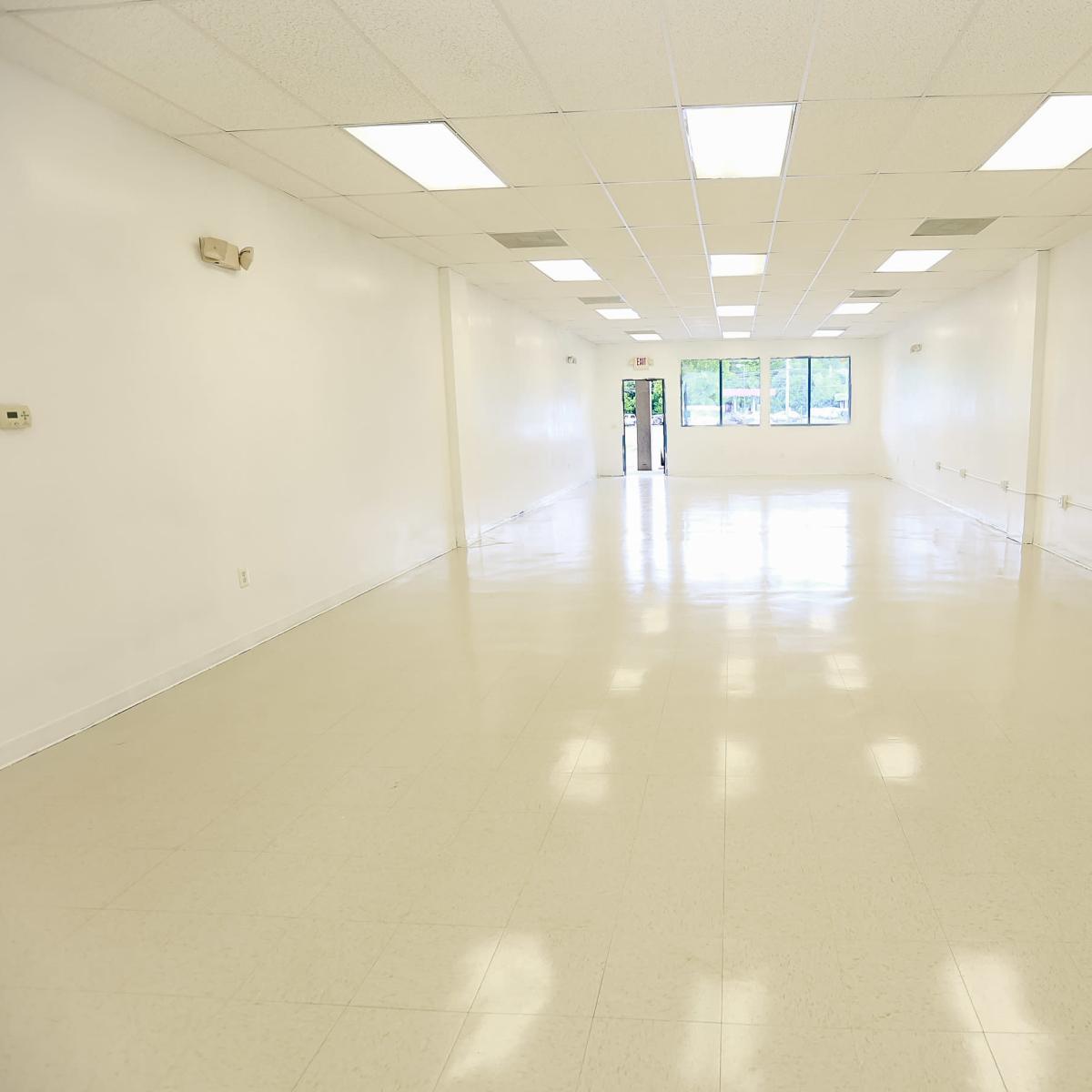 A large, empty, well-lit room with white walls and a glossy floor.