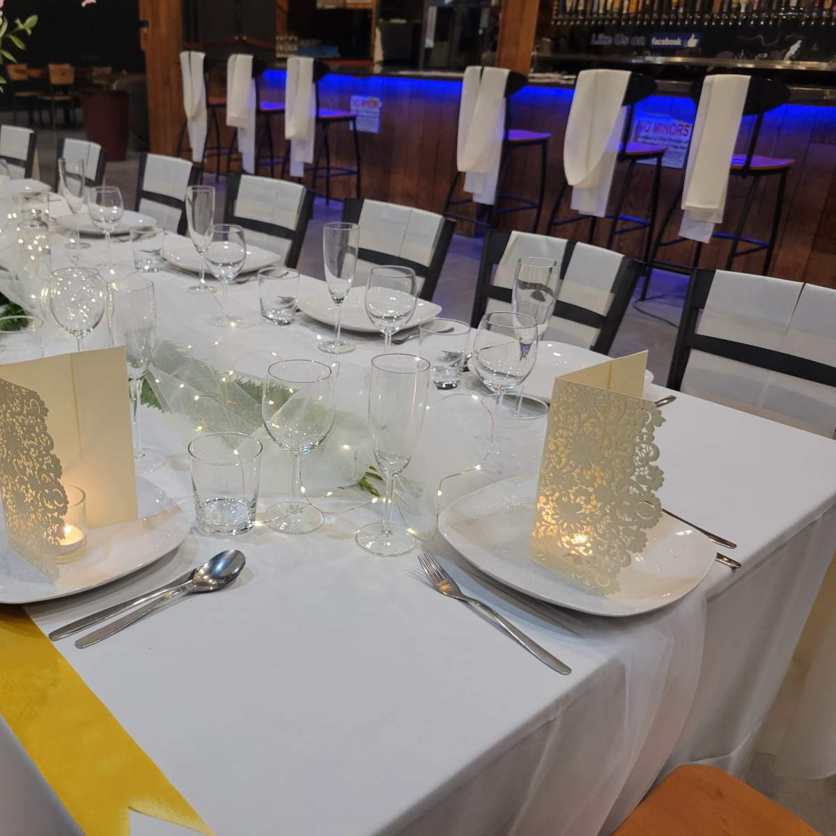 A beautifully set dining table with decorative plates, glassware, and illuminated candles arranged for a formal event.