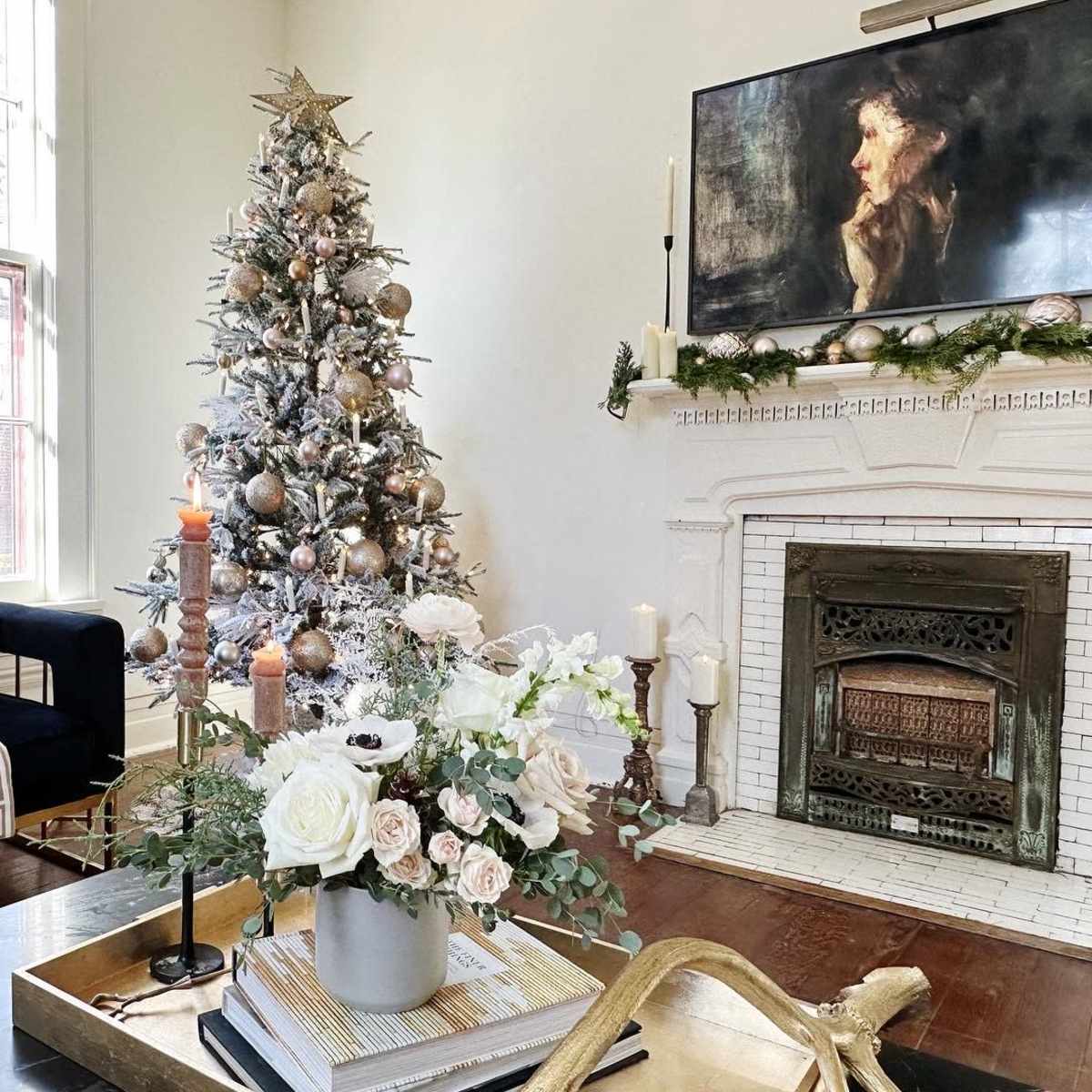 A decorated living room with a Christmas tree, a fireplace adorned with candles, and a stylish armchair beside a coffee table.
