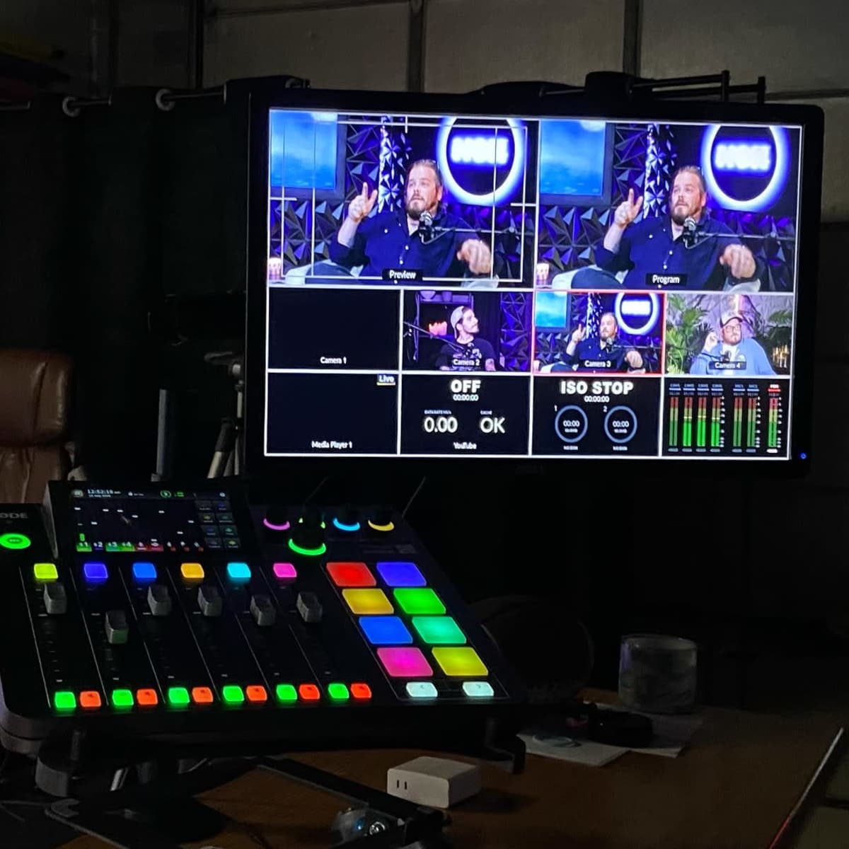 A control panel with colorful buttons and a monitor displaying multiple video feeds and a recording interface.