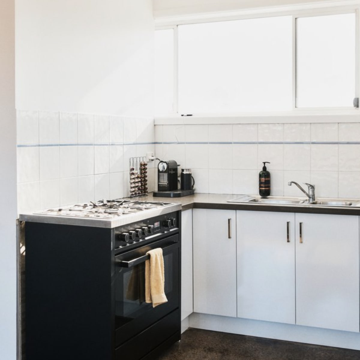 A modern kitchen with a gas stove, stainless steel appliances, and white cabinetry.