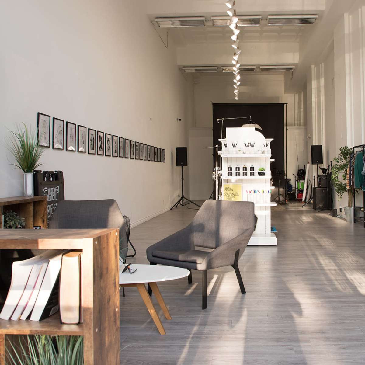 A spacious interior of a design studio featuring modern furniture, framed artwork on the walls, and display areas for products.