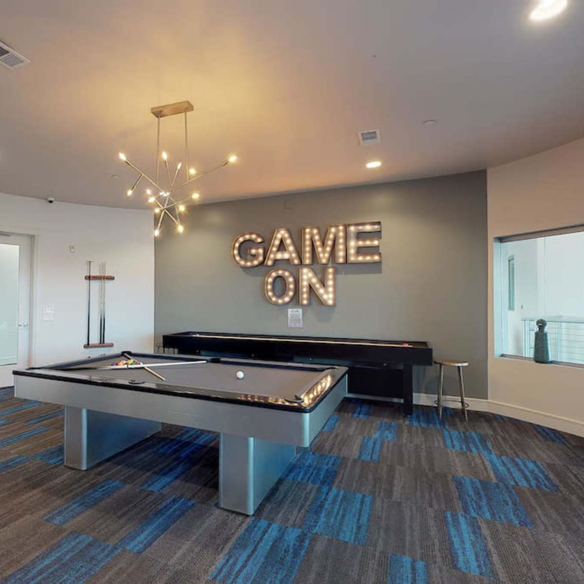 A game room features a black pool table, decorative wall art, and a prominent "GAME ON" sign illuminated above.