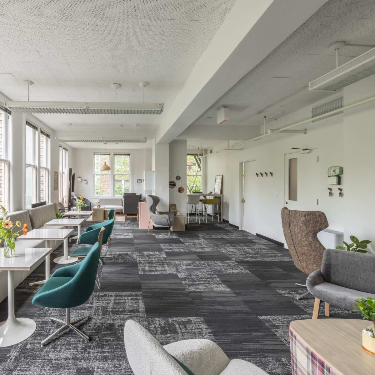 A spacious modern lounge area with large windows, various seating options, and a mix of tables and chairs.