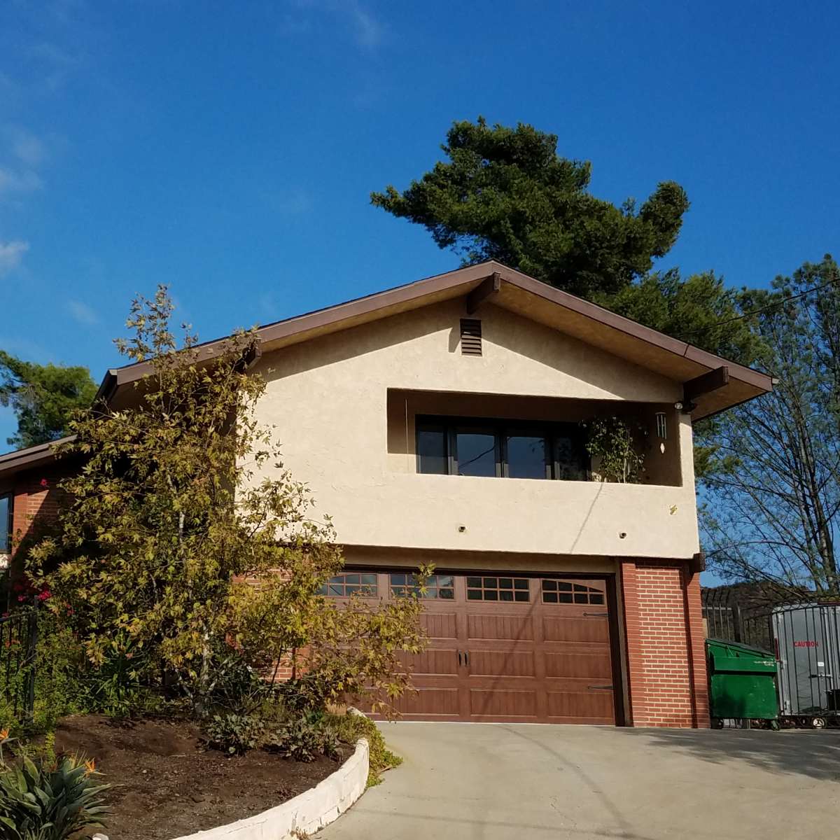 A modern two-story house with a brick and stucco exterior, featuring a garage and landscaped front yard.