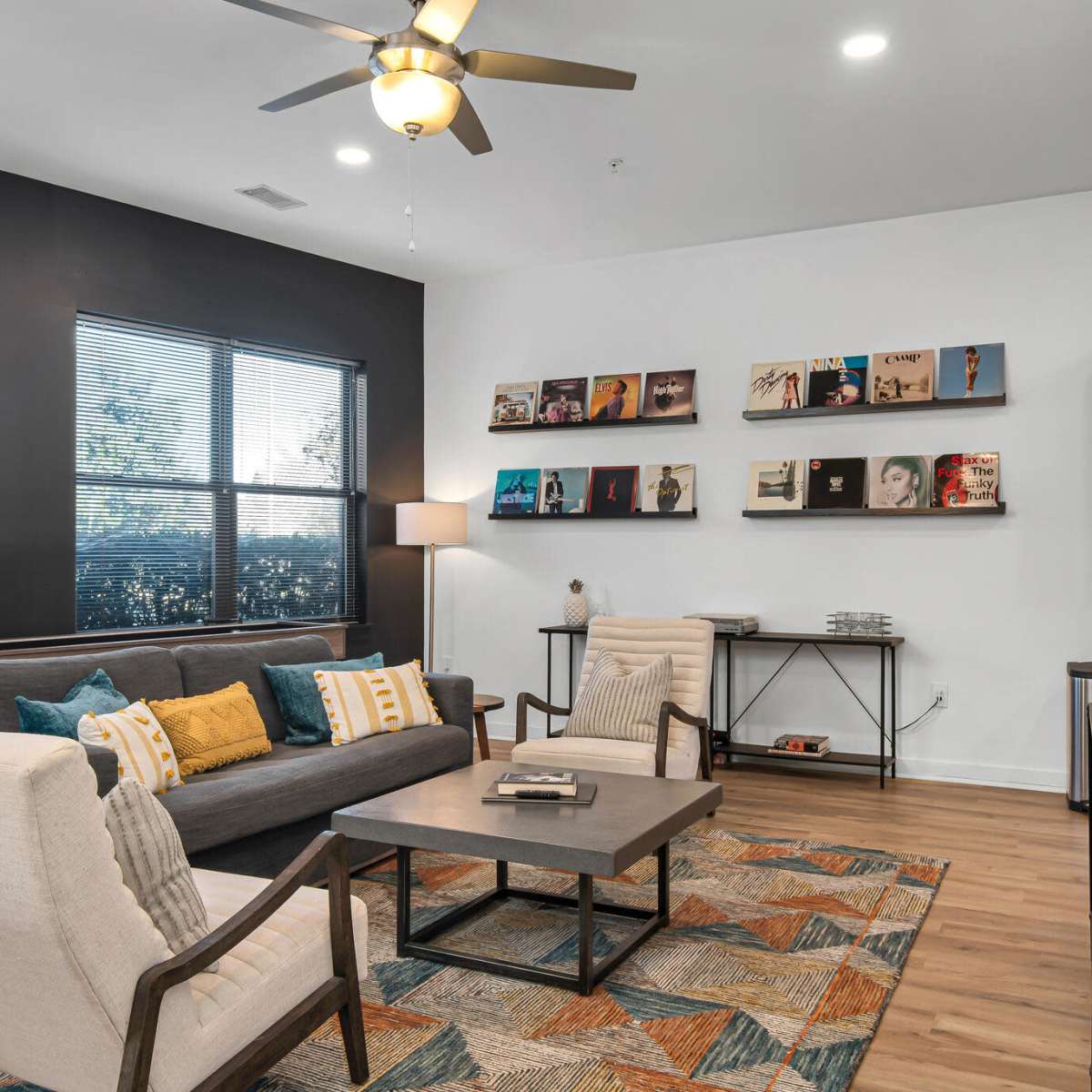 A modern living room with a gray sofa, two chairs, a coffee table, and a wall displaying framed artwork.