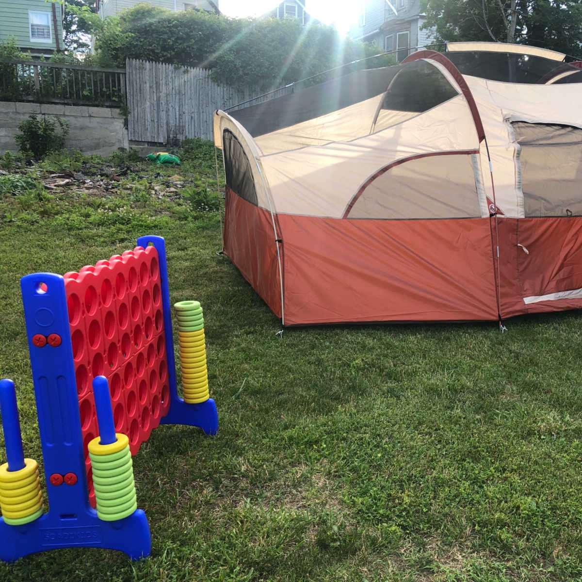 A large tent is set up on a grassy area next to a colorful Connect Four game.
