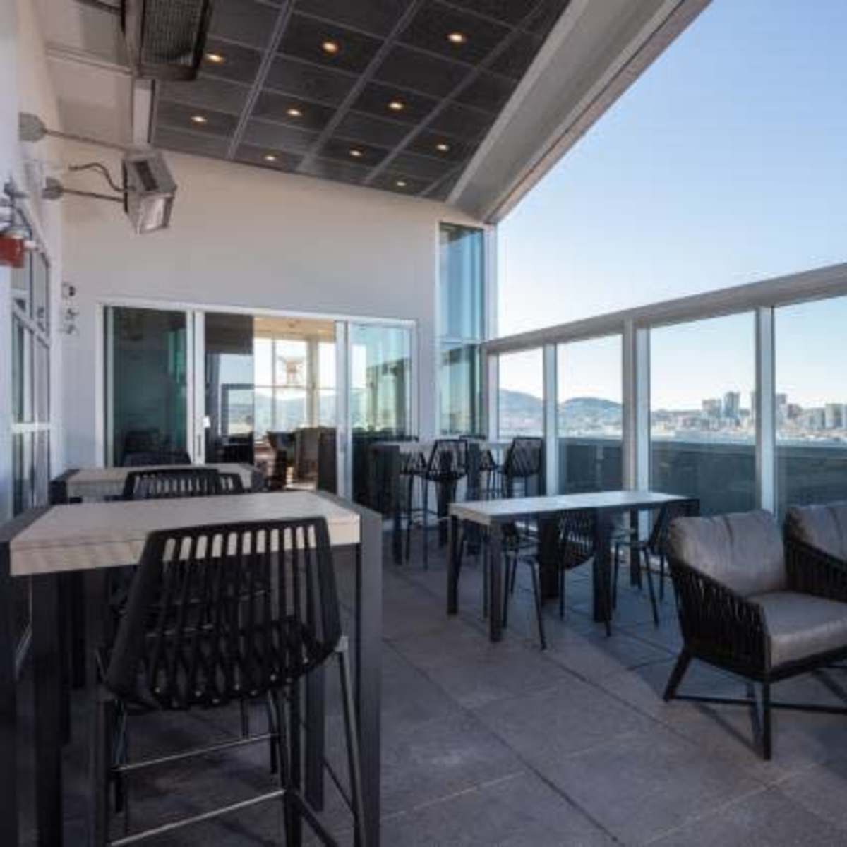 A rooftop terrace features a set of tables and chairs with city skyline views in the background.