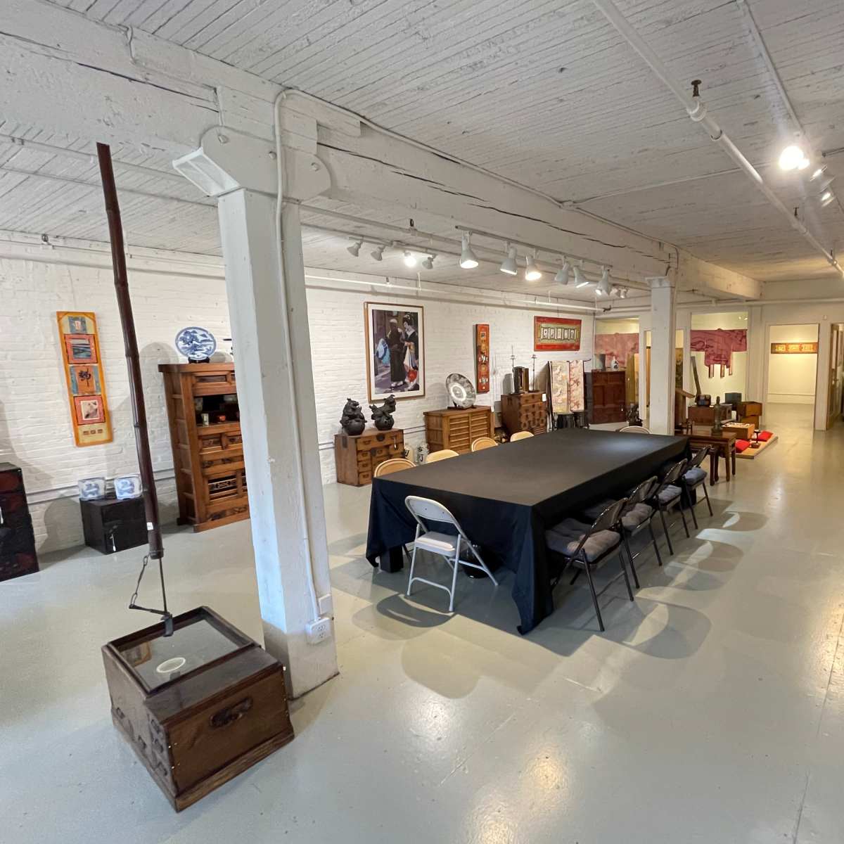 A spacious room with a long table surrounded by chairs, flanked by wooden furniture and decor on the walls.