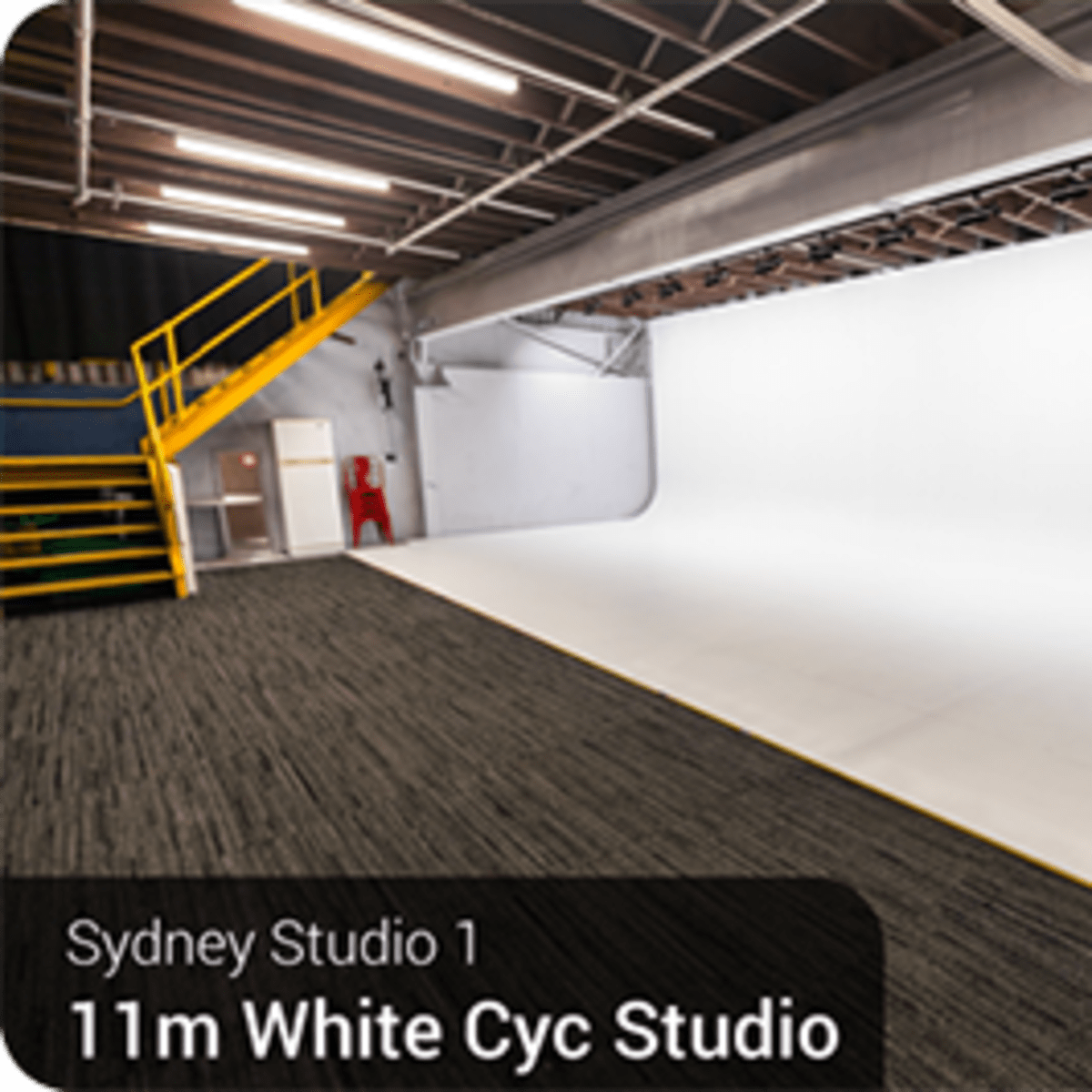 A large white cyc studio with a seamless backdrop and a staircase leading to an upper level.