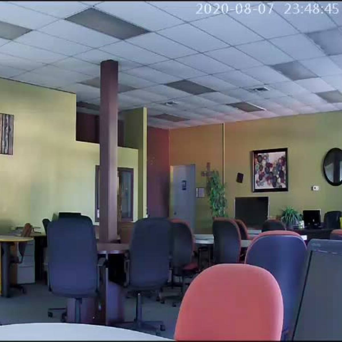 A spacious office interior with several desks and computer stations, along with a few chairs and decorations on the walls.