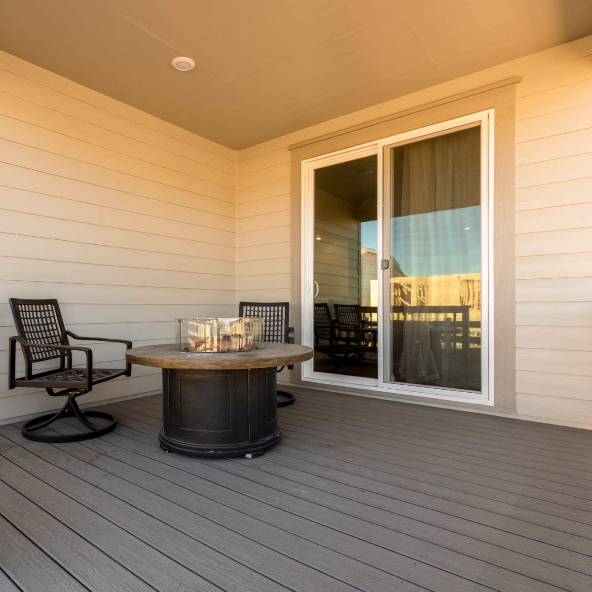 A small outdoor patio with a round table and two chairs beside a sliding glass door.