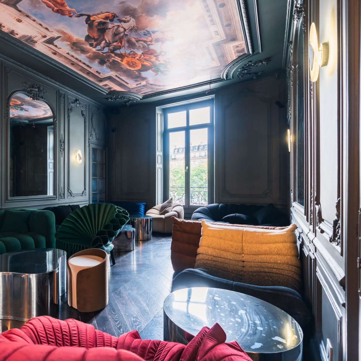 An elegant interior with decorative walls and a painted ceiling, featuring various modern furniture pieces in different colors and textures.