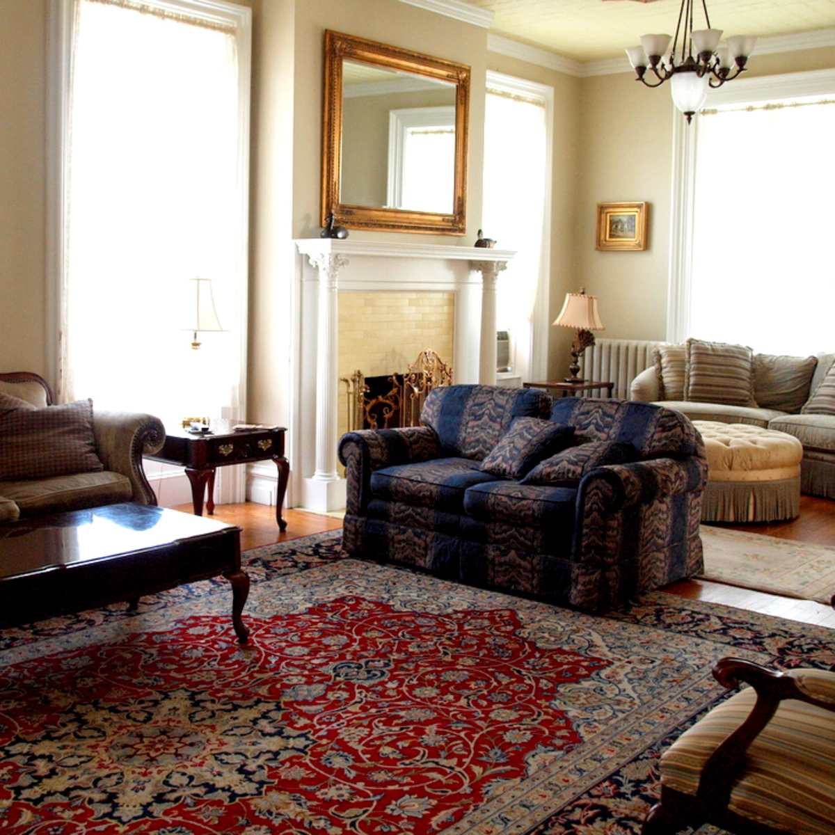 A living room with a patterned area rug, a wooden coffee table, and two sofas arranged around a fireplace.