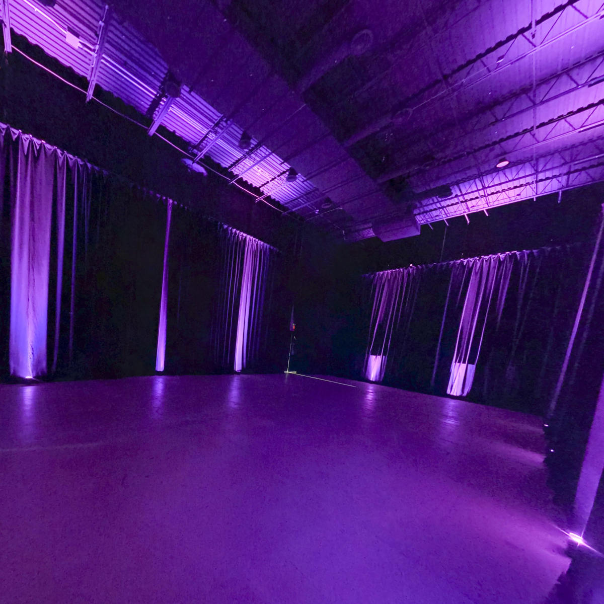 A dimly lit performance space with purple curtains and lighting.