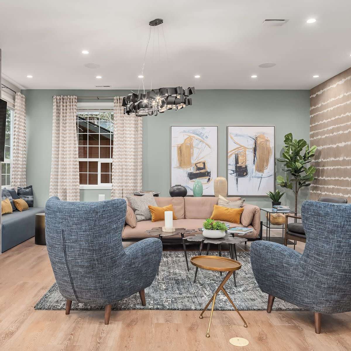A modern living room featuring a cozy sofa, two large armchairs, a contemporary coffee table, and a wall-mounted television above a fireplace.