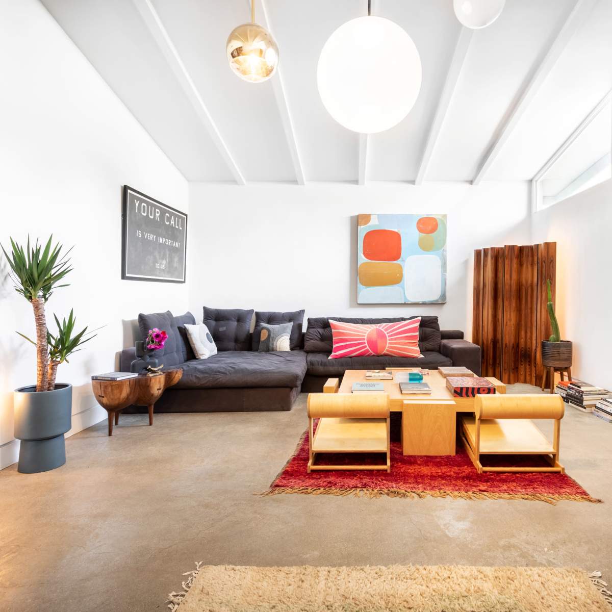 A modern living room featuring a large sectional sofa, a coffee table, a decorative rug, and a fireplace with artwork on the walls.